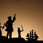 Marooned pirates watch as their ship sails away into the sunset.