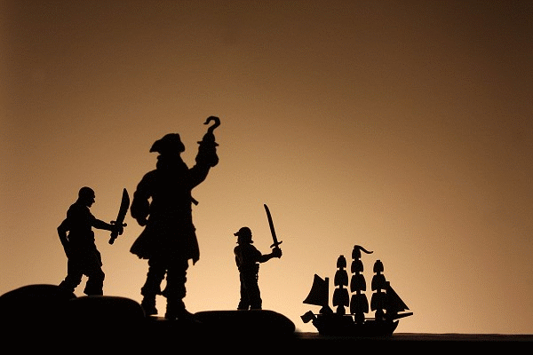 Marooned pirates watch as their ship sails away into the sunset.
